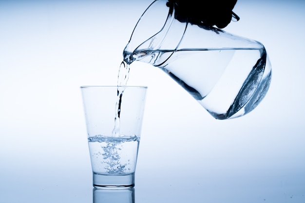 Vaso de agua con vertido de la botella, Foto de estudio