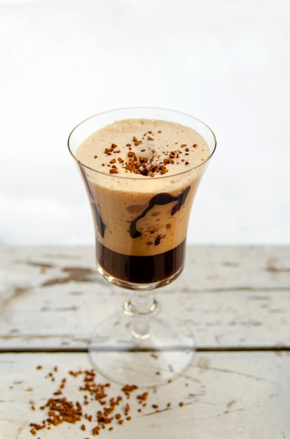 Vaso alto de café con hielo fresco con frijoles en el tablero rústico blanco