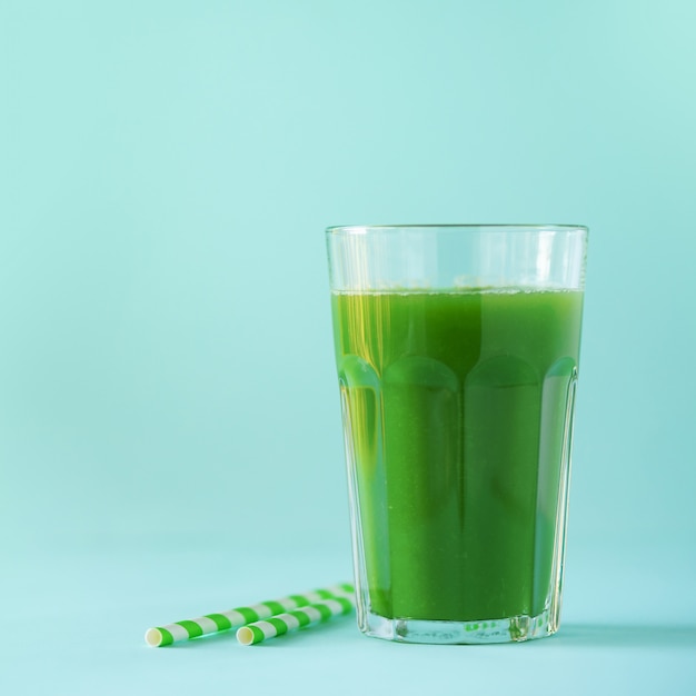 Vaso de batido de apio verde sobre fondo azul