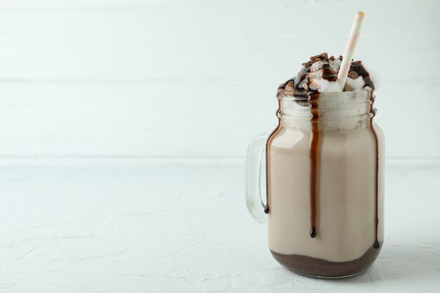 Vaso de batido de chocolate en la mesa con textura blanca