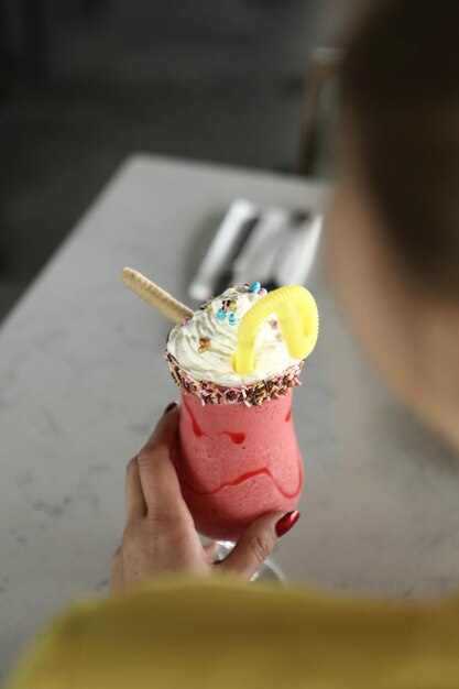 Vaso de batido de frambuesa con crema batida y frambuesas frescas