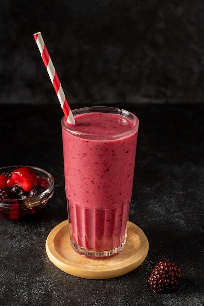 Un vaso de batido de frambuesa con una pajita de rayas rojas y blancas.