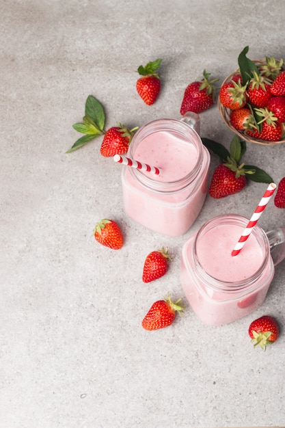 Un vaso de batido de fresa fresca sobre un fondo gris