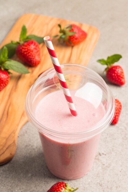 Un vaso de batido de fresa fresca sobre fondo rosa