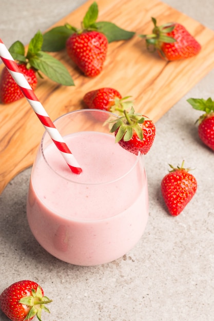 Un vaso de batido de fresa fresca sobre fondo rosa