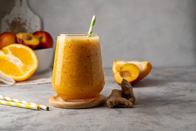 Vaso de batido de naranja hecho con jengibre de melocotón y espacio de copia de naranja