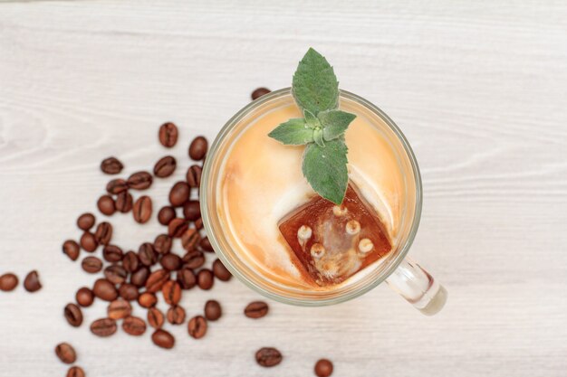 Vaso de batido o batido con hielo de chocolate y hojas de menta con granos de café.