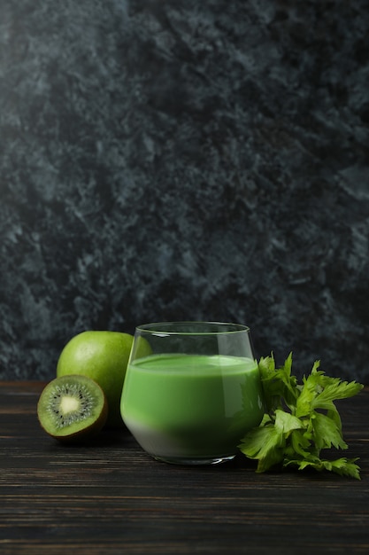 Foto vaso de batido verde e ingredientes sobre mesa de madera