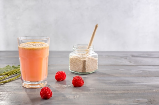 Un vaso de batidos a base de bayas de rubus illecebrosus y leche de coco con cáscaras de semillas de psyllium