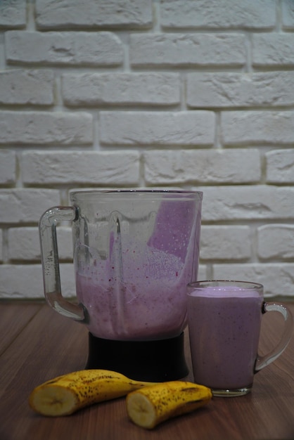 Un vaso de batidos en la mesa junto a un plátano en rodajas