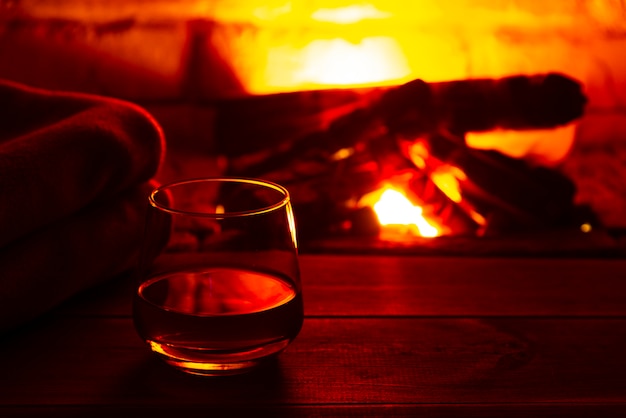 Vaso de bebida alcohólica vino delante de la cálida chimenea. ambiente mágico relajado y acogedor cerca del fuego