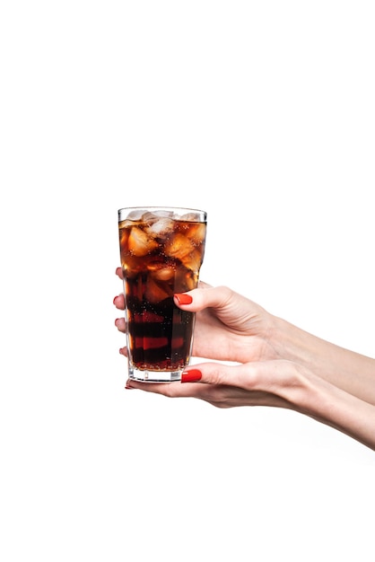 Vaso de bebida gaseosa con hielo en mano femenina aislado sobre fondo blanco.