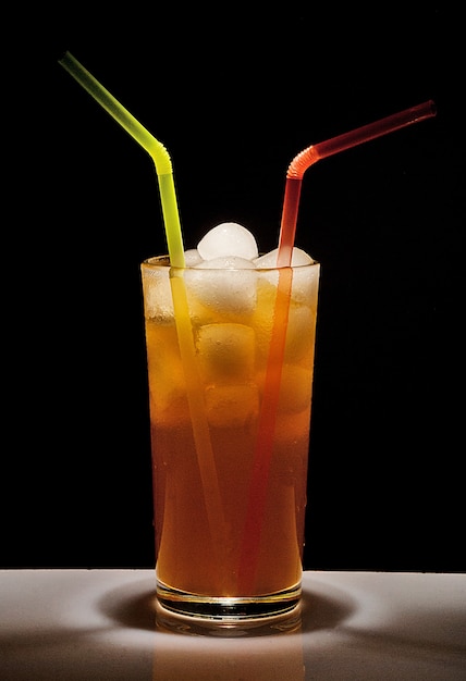 Vaso con una bebida y hielo sobre fondo negro