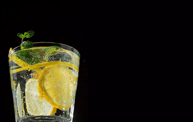 Un vaso con bebida de limonada con limón y menta