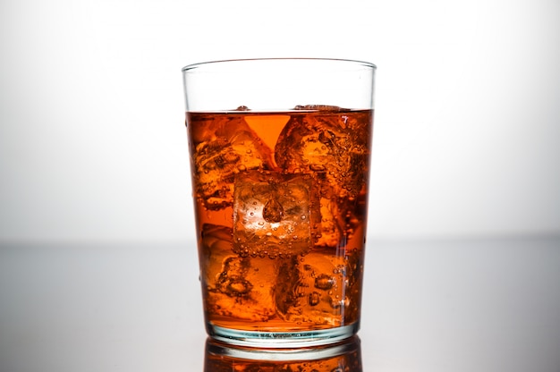 Un vaso de bebida de naranja con cubitos de hielo.