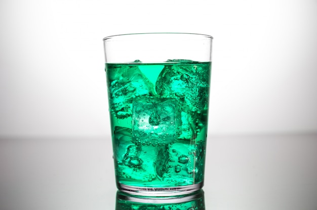 Un vaso de bebida verde con cubitos de hielo.