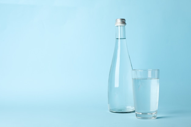 Vaso y botella con agua en azul, espacio para texto