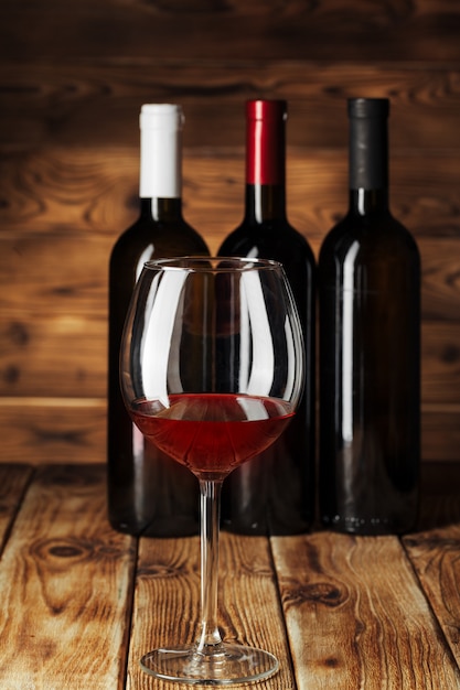 Vaso y botella con delicioso vino tinto en la mesa