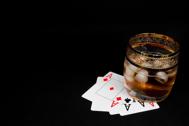 Vaso de brandy de whisky rojo oscuro o xAbourbon con hielo aislado sobre fondo negro Foto de cierre de alcohol