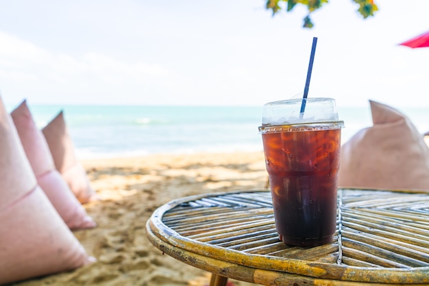 Vaso de café americano negro con fondo de mar