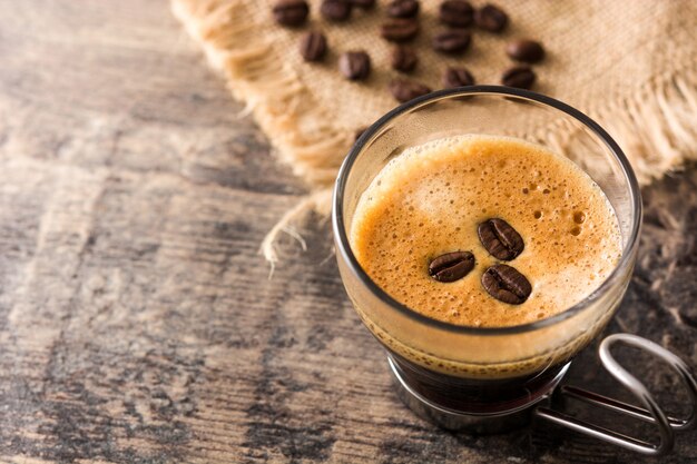 Vaso de café y café en grano en la mesa de madera