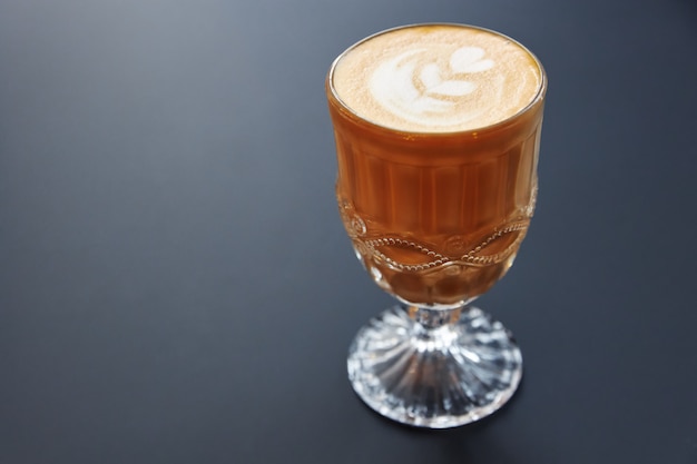 Vaso de café con espuma con un patrón sobre una superficie gris