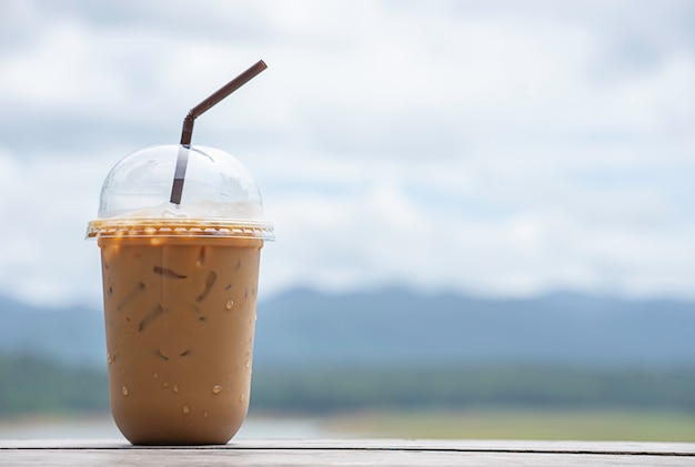 Foto vaso de café exprés frío sobre la mesa fondo borrosa vistas cielo agua y montaña.