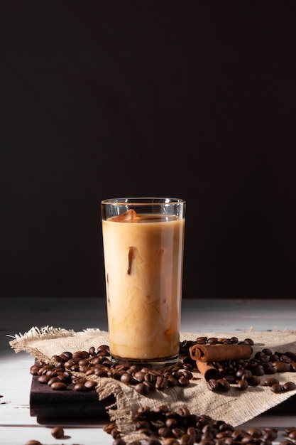 Un vaso de café frío y nata. Granos de café