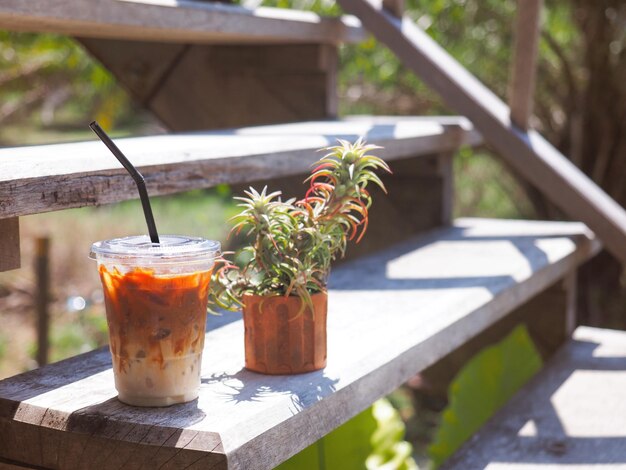 Vaso de café helado en escalera vintage de madera