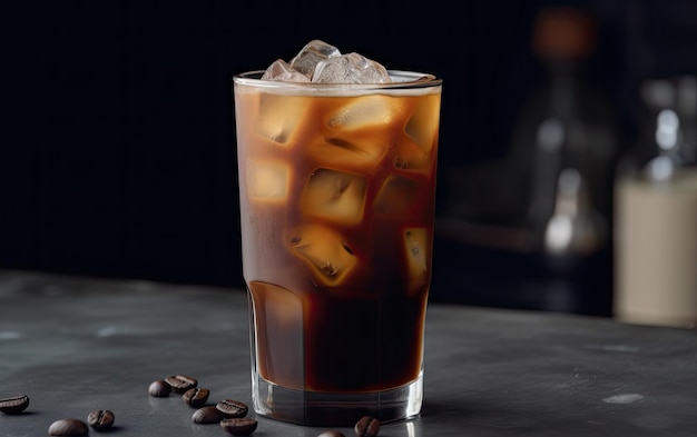 Un vaso de café helado con hielo en un mostrador negro.