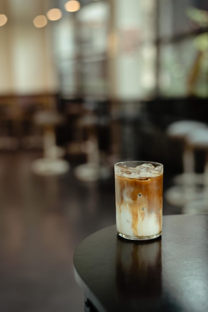 Un vaso de café helado se sienta en una mesa frente a un bar.