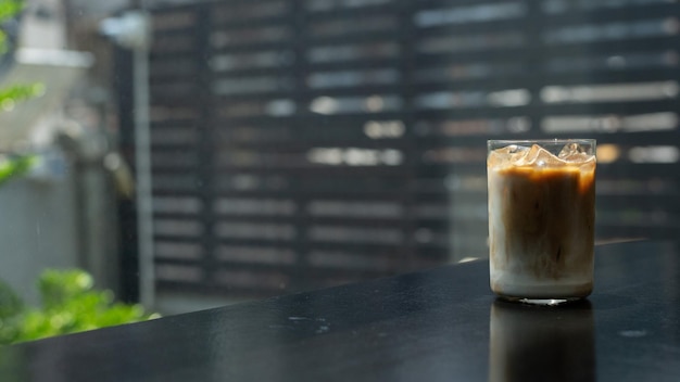 Un vaso de café helado se sienta sobre una mesa con un fondo negro.