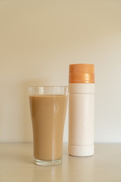 Vaso de café con leche con botellas de café listas para beber en la mesa