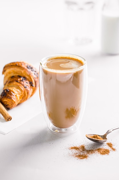 Vaso de café con leche con croissant en blanco