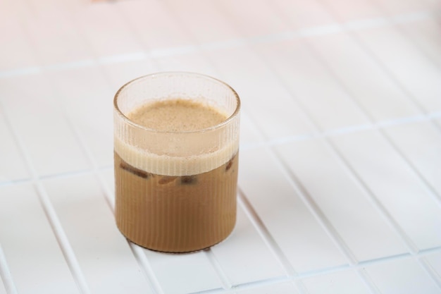 Un vaso de café con leche helado en la mesa blanca