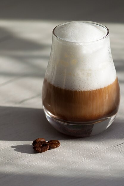 Vaso con café con leche con leche o capuchino por la mañana. La luz del sol, el concepto de buen día.