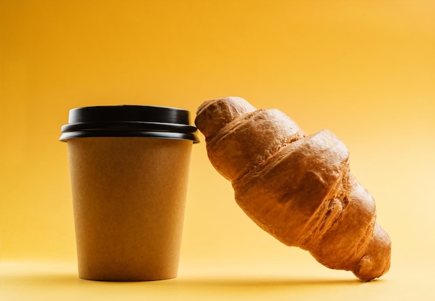 Un vaso de café y un primer plano de croissant sobre un fondo amarillo.
