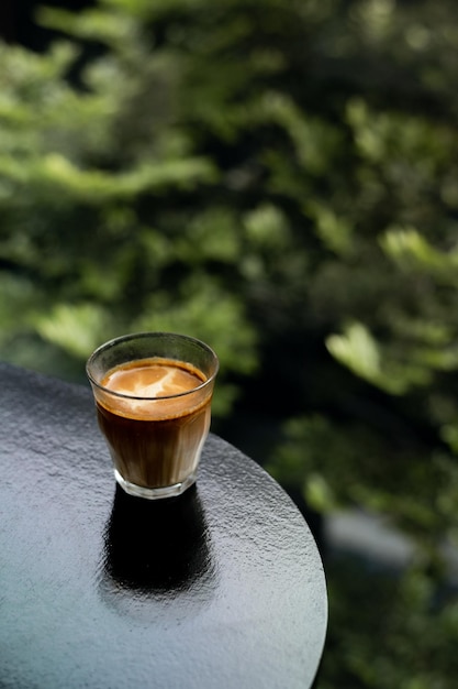 Un vaso de café se sienta en una repisa con un fondo verde