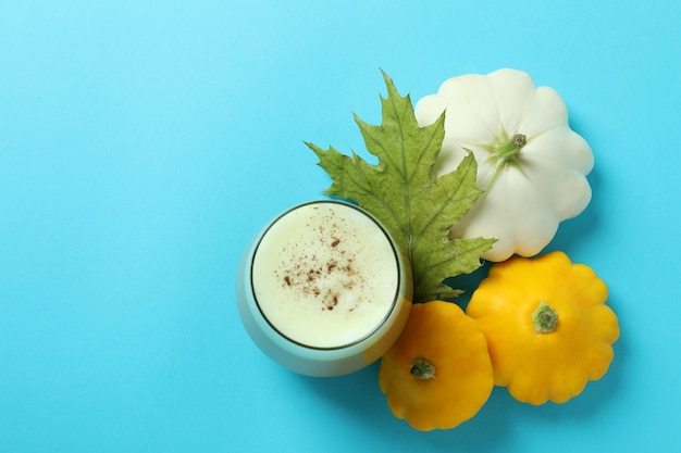 Vaso de calabaza con leche e ingredientes sobre fondo azul.