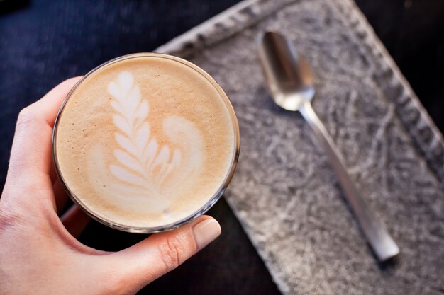 Un vaso de capuchino con espuma y un patrón