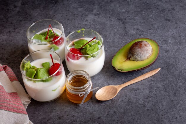 Vaso de cereza y aguacate en rodajas en el yogur sobre fondo de madera.