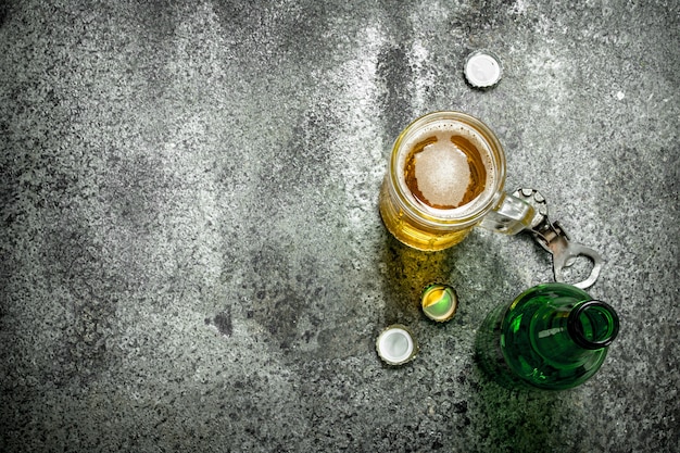 Vaso de cerveza con un abrebotellas y tapones sobre un fondo rústico