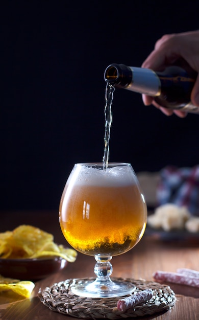 Vaso de cerveza artesanal, mesa de madera oscura.