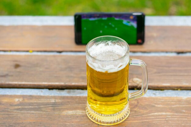 vaso de cerveza en un banco del parque en un parque público naturaleza verde primavera verano teléfono móvilteléfono inteligente