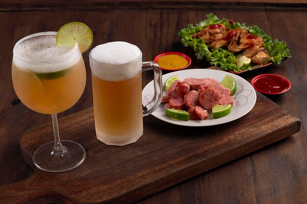 Vaso de cerveza y bebida cozumel en una tabla de madera con pociones de pollo frito y salchicha frita