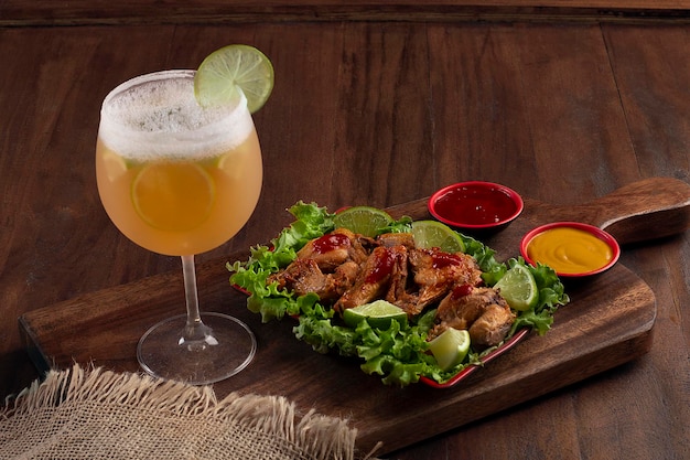 Vaso de cerveza y bebida cozumel en una tabla de madera con pociones de pollo frito y salchicha frita