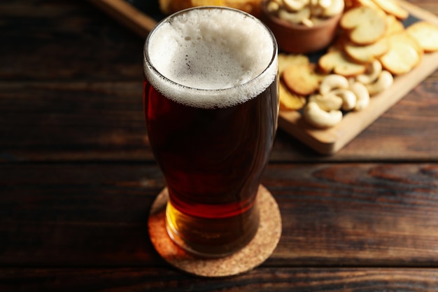 Vaso de cerveza y bocadillos en la mesa de madera