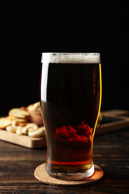Foto vaso de cerveza y bocadillos en la mesa de madera