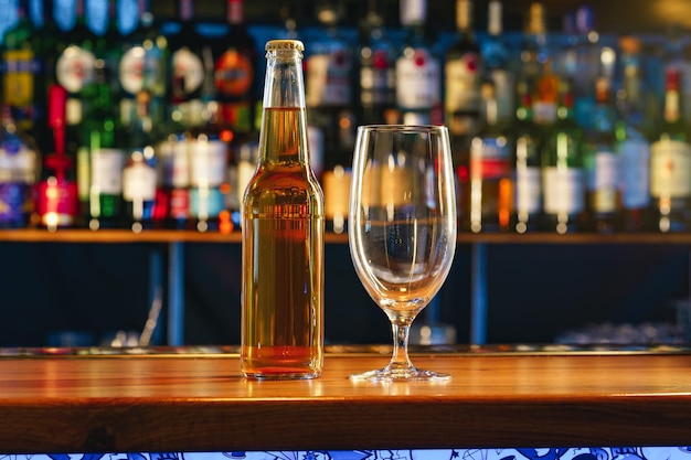 Vaso de cerveza y botella en encimera de madera en un pub