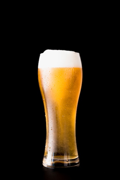 Foto vaso de cerveza delante de fondo negro